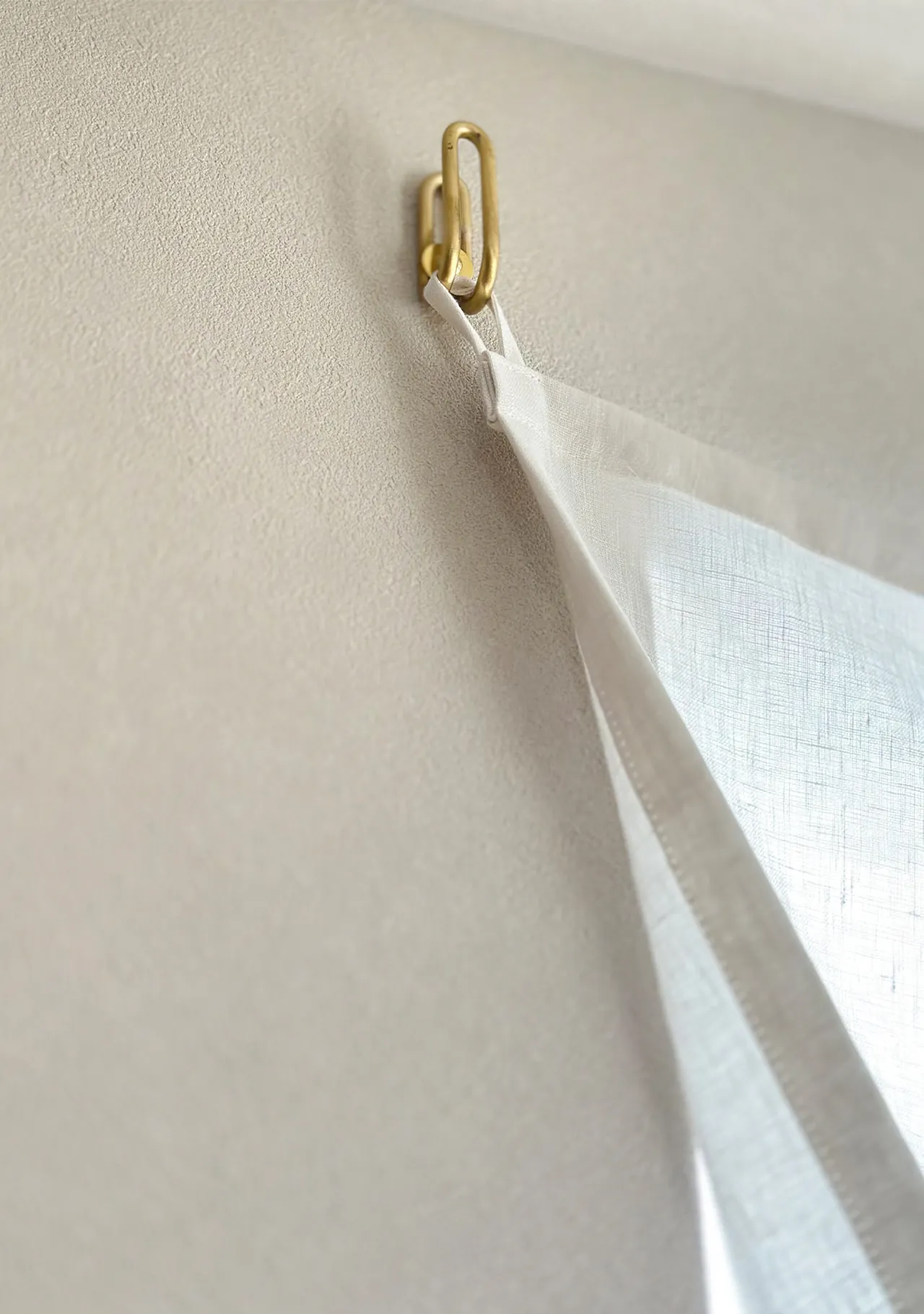 ふさかけに直接引っ掛けられるよう縫製されたリネンカーテン。金具に軽やかに掛かる様子